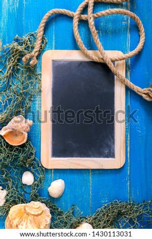 Tropical sea background. Different shells, old fishing net on the blue boards, top view. Free space for inscriptions on the slate. Summer theme.