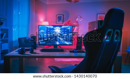 Powerful Personal Computer Gamer Rig with First-Person Shooter Game on Screen. Monitor Stands on the Table at Home. Cozy Room with Modern Design is Lit with Pink Neon Light. Royalty-Free Stock Photo #1430140070