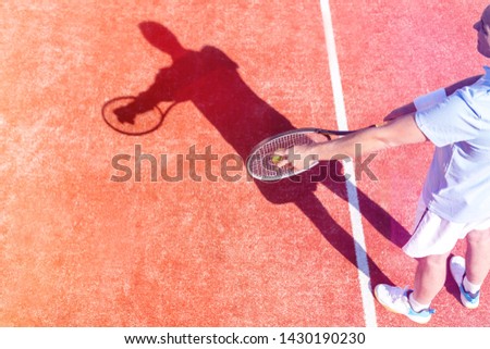 High angle view of mature man serving tennis ball on red court