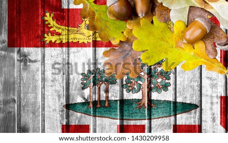 Prince Edward Island flag on autumn wooden background with leaves and good place for your text.