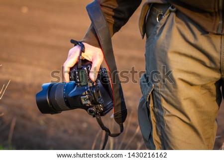 Camera in hand. Photographer holding digital camera outdoors. Adventure in nature