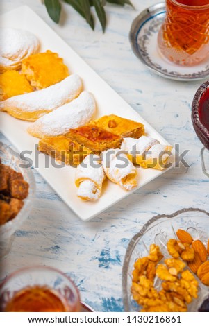 Tea set with varieties of traditional nuts, lemon, confiture and sweets served on white tablecloth - Image