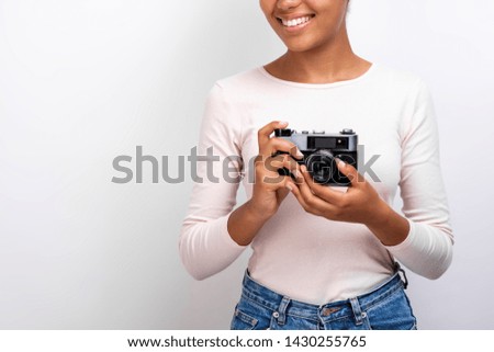 Cropping studio image of a traveller girl holding photo camera in her hands - Image