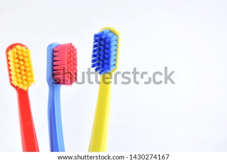 Colorful toothbrushes with selective focus on blurred neutral background. Dental tools for daily teeth protection. Multicolored plastic toothbrush with bright bristles with soft focus. Oral hygiene 
