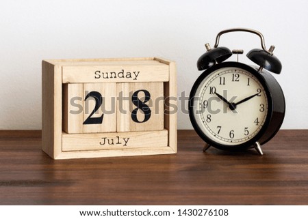 Wood calendar with date and old clock. Sunday 28 July