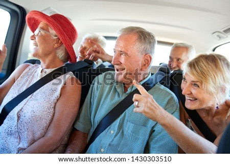 Group Of Senior Friends Sitting In Back Of Van Being Driven To Vacation Royalty-Free Stock Photo #1430303510