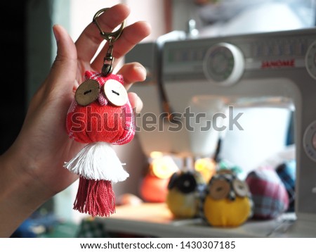 Hand holding Owl Doll made from hand woven fabric and bokeh background, Owl doll key-ring and blurred background, Handmade Concept.
