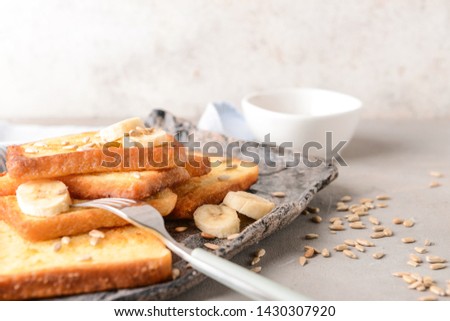 Plate with tasty French toasts and banana on grey table
