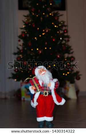 Santa Claus at Christmas time, with a Christmas tree behind, with gifts and bokeh
