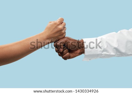 Friends greetings sign or disagreement. Two male hands competion in arm wrestling isolated on blue studio background. Concept of standoff, support, friendship, business, community, strained relations.
