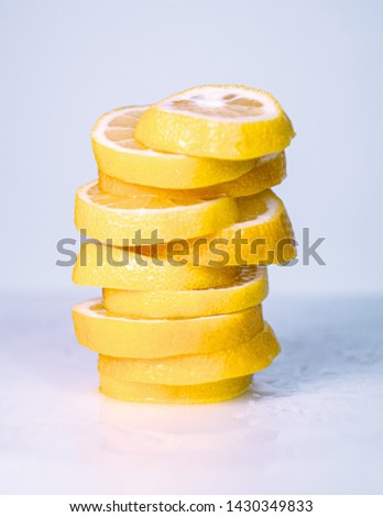 Yellow lemon cutted into slices on light desk, close up view. Lemon slices piled together. Pile of yellow slices. Blurred background. Selective soft focus