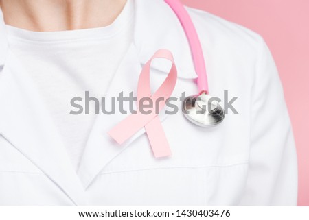 close up view of doctor in white coat with pink breast cancer sign and stethoscope isolated on pink