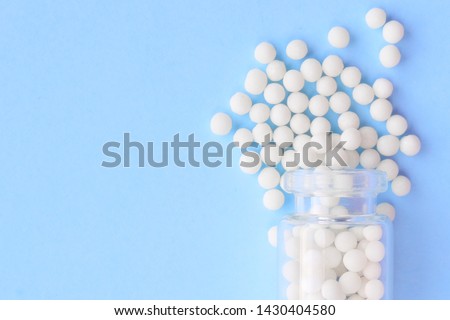 Homeopathic globules and glass bottle on blue background. Alternative Homeopathy medicine herbs, healtcare and pills concept. Flatlay. Top view. copyspace for text. Royalty-Free Stock Photo #1430404580