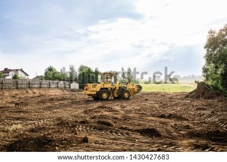 large yellow wheel loader aligns a piece of land for a new building Royalty-Free Stock Photo #1430427683