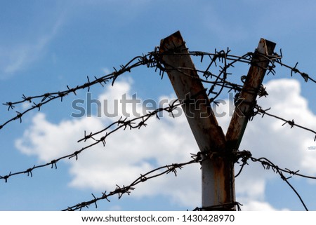 barbed wire fence with blue sky and clouds background.