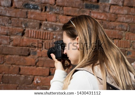 photographer takes pictures on camera against a brick wall