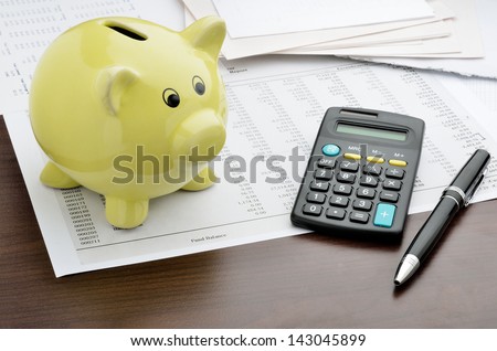 Piggy bank with calculator and business reports Royalty-Free Stock Photo #143045899