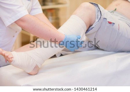 Nurse bandages the leg. Fracture of human lower limbs. Treatment of broken bones. Impose a gypsum. Patient surgical department. The doctor's hands tighten the bandage on his leg Royalty-Free Stock Photo #1430461214