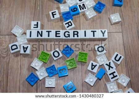 Selective focus of INTEGRITY text from plastic cubic alphabets in wooden background. 
