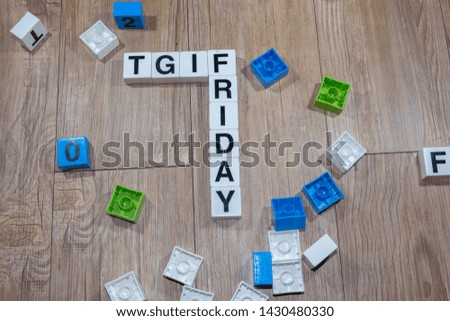 Selective focus of TGIFRIDAY text from plastic cubic alphabets in wooden background. 