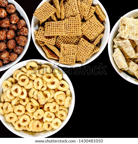 Selection Of Bowls Of Healthy Eating Breakfast Cereal Including Shredded Wheat Chocolate Shreddies and Cheerios, On A Black Background