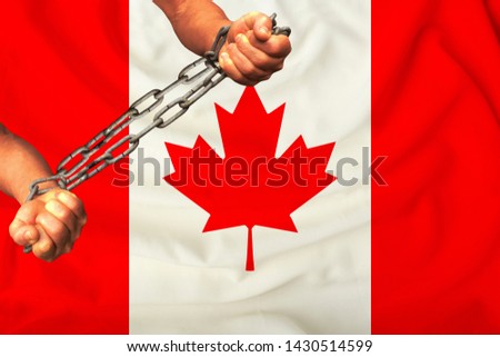 men's hands chained in heavy iron chains against the background of the flag of Canada on a gentle silk with folds in the wind, the concept of the movement in support of human rights