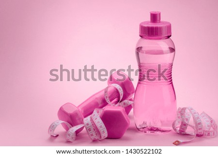 Dumbbels, measuring tape and bottle of water on pink background. Burn calories, weight loss and fitness.