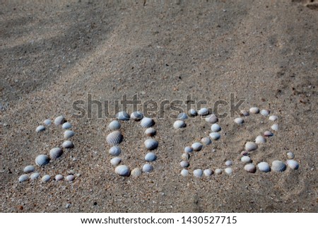 The figure "2022" is laid out on the sand with shells. There is free space, space for text.