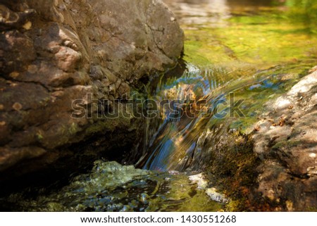 Mountain stream flowing between huge stones covered with moss
