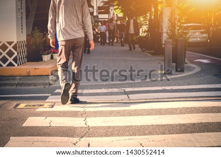 Men are walking across the crosswalk in the morning of workday in sunshine.