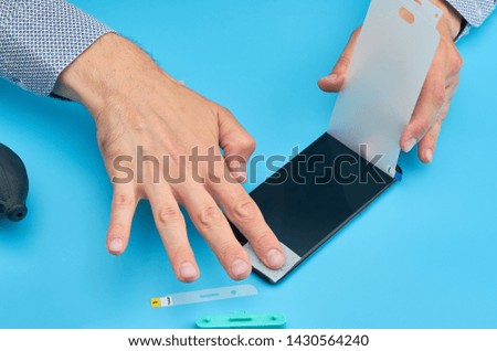 Hand of man replacing the broken tempered glass screen protector for smartphone.