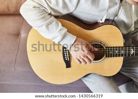 Cropped shot of man practicing in playing acoustic guitar. Close-up of man hand playing guitar.