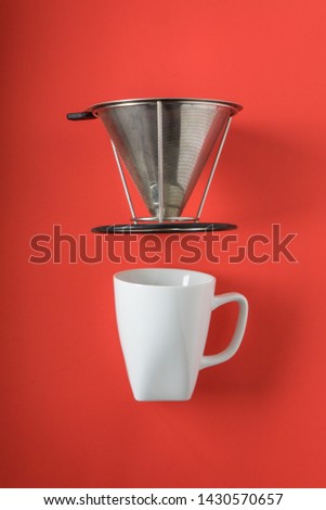 White coffee mug on red background with filterless metal pour over drip cone with blank empty room space for text, copy, or copyspace. Top view of flat lay fresh gourmet cup mock up.