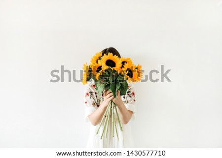 Young pretty woman in white dress hold sunflowers bouquet on white background. Floral minimal composition.