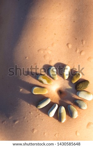 Pattern of small sea stones on women's skin, pebble beach