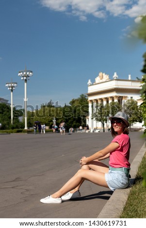 Woman in hat sitting on the border in the park, Moscow.