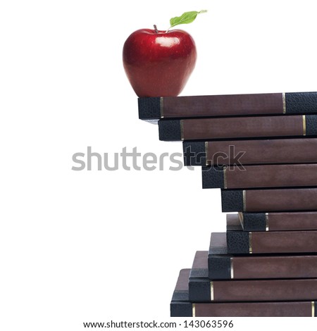 A red apple sitting on stack of books on white background, shot close-up