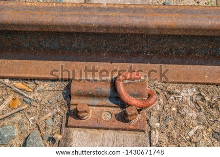 Rusty old train track rail bolted down with a plate and bolts to a wooden tie
