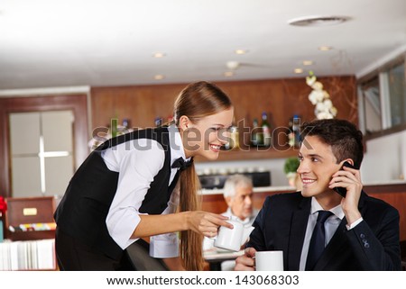 Waiter offering a pot of coffee to business man in hotel cafÃ?Â?Ã?Â© Royalty-Free Stock Photo #143068303
