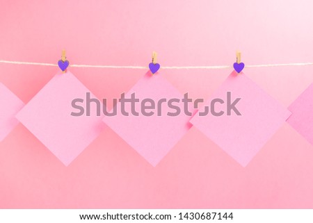 Pink stickers on clothesline with clothespins isolated on pink background. Place for your text.