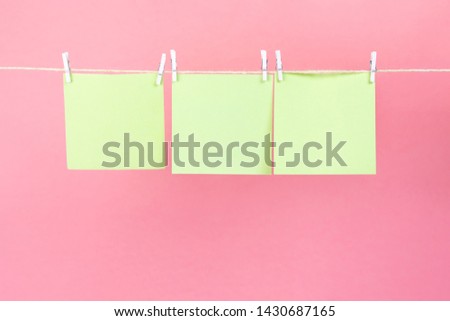Yellow stickers on clothesline with clothespins isolated on pink background. Place for your text.