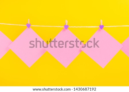 Pink stickers on clothesline with clothespins isolated on yellow background. Place for your text.