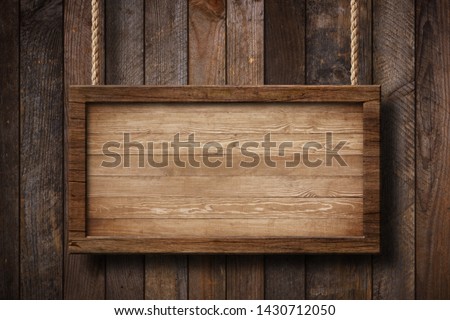 Large wooden sign hanging on ropes with wood planks background