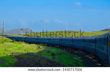 Side view of passenger coaches in Indian railway running between Mumbai and Goa with green landscape.