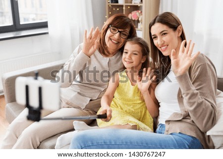 family, generation and technology concept - happy mother, daughter and grandmother taking picture by selfie stick at home