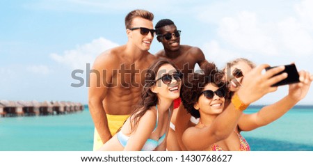 friendship, summer holidays and people concept - group of happy friends taking picture by smartphone over tropical beach background in french polynesia