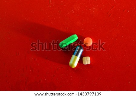 Medical or vitamin pills on red background. Colorful pill texture.