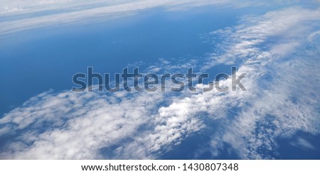 Picture of the blue cloudy sky view from an airplane window seat.