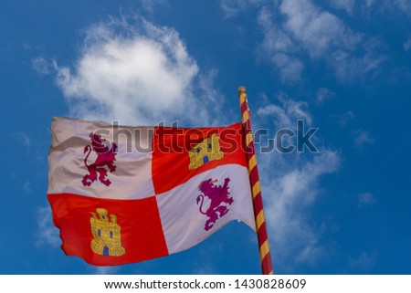 Flag of the community of Castilla and Leon, waving on a blue and sunny sky with small clouds. Mast decorated with the colors of Spain