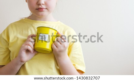 A girl in a yellow T-shirt with a yellow cup in her hand, on which was written Did you know